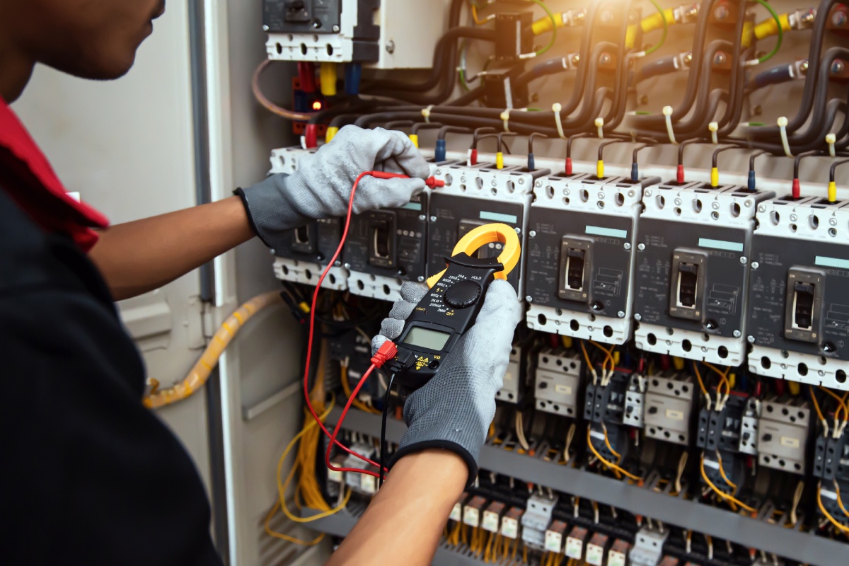Électricien contrôlant un tableau électrique au multimètre